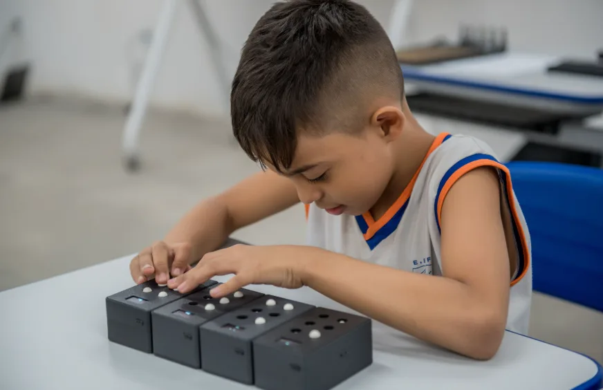 Estudante formando letras com os blocos do EdukaBraille