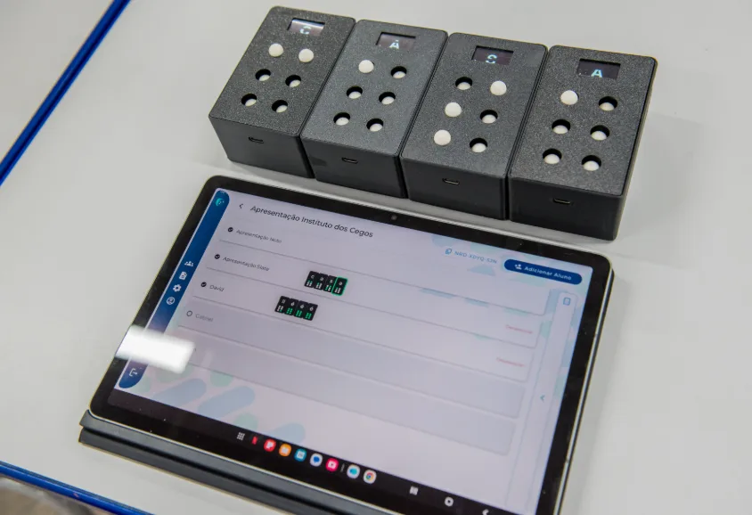 Blocos do EdukaBraille ao lado do tablet com o aplicativo Sala Braille aberto